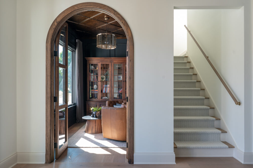 Huyck house bourbon room inside an arched doorway. A staircase leading upstairs is to the right.
