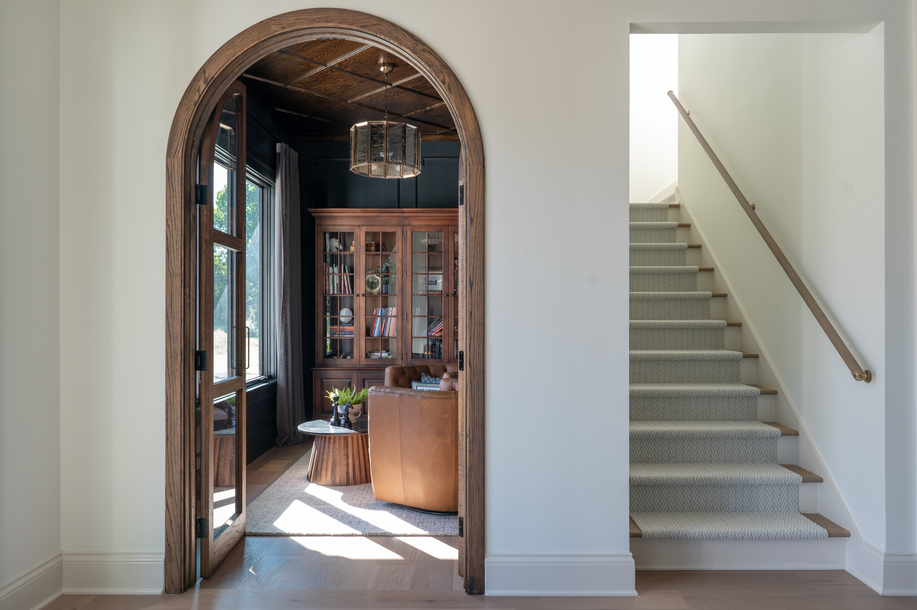 Huyck house bourbon room inside an arched doorway. A staircase leading upstairs is to the right.