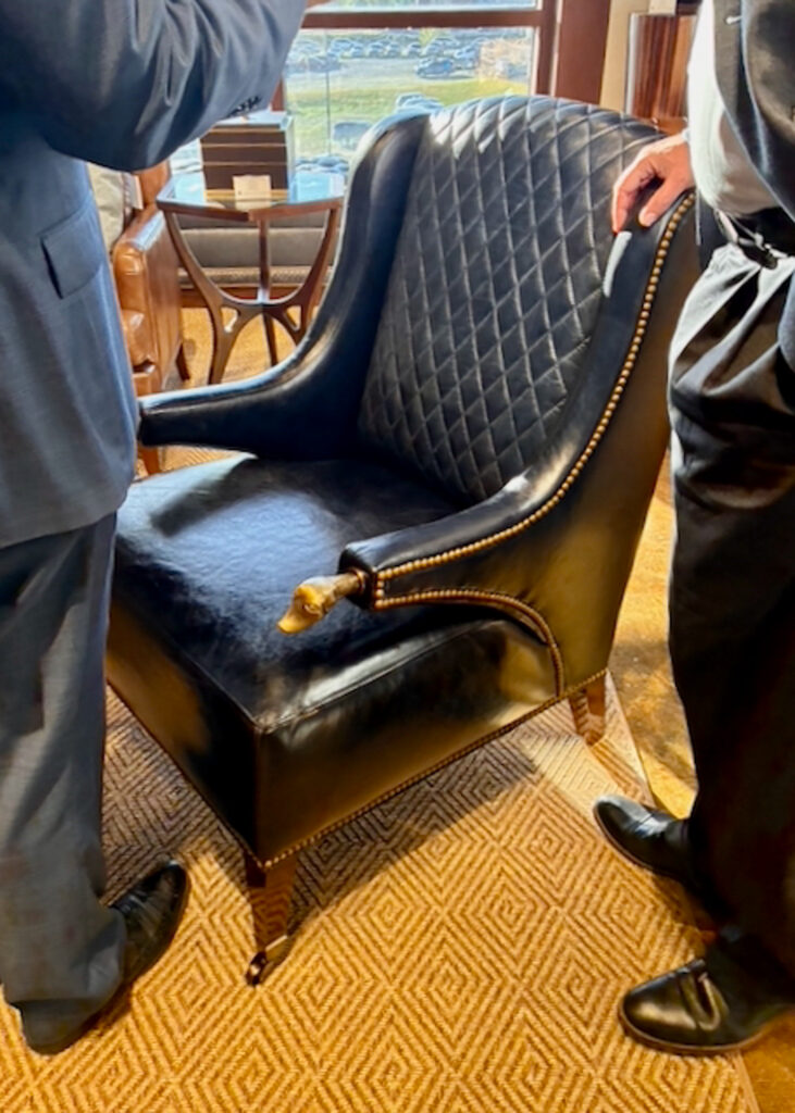 Black leather accent chair with quilted upholstery, brass nailhead trim and decorative arm details.
