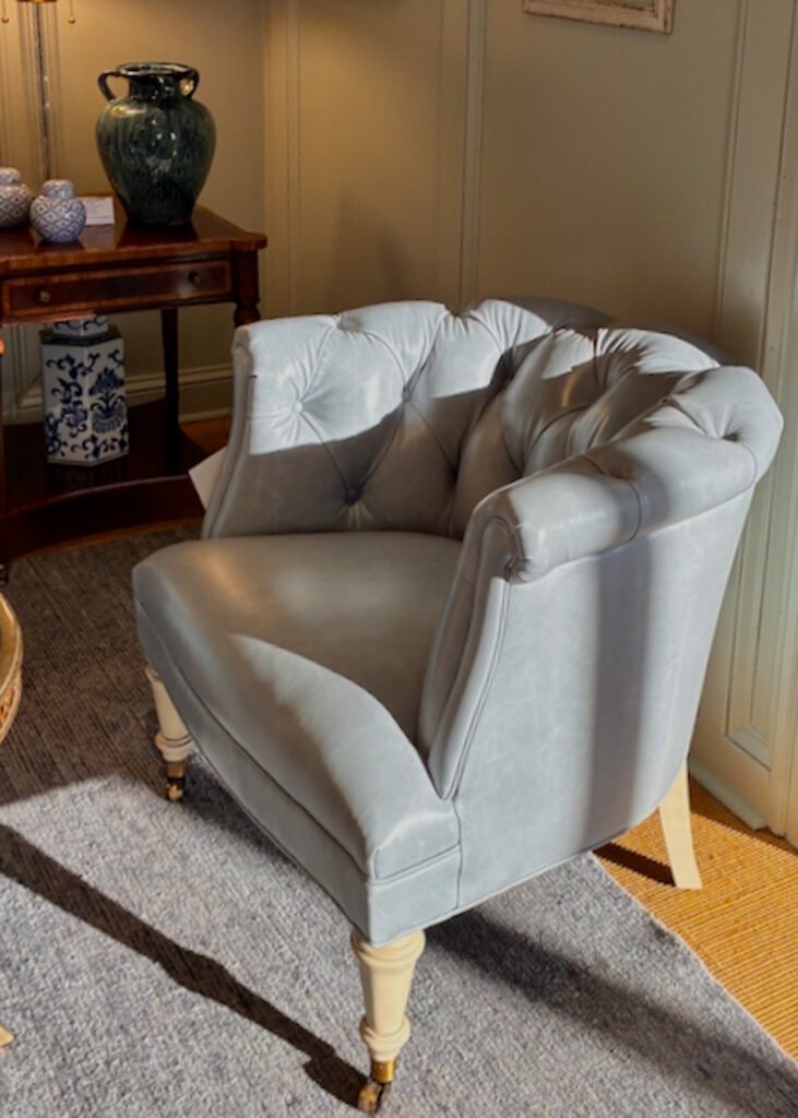 Light blue upholstered accent chair with tufted back, curved arms and turned legs.